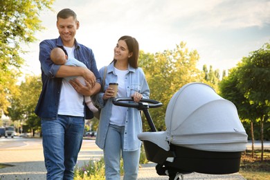 Photo of Happy parents walking with their baby in park on sunny day