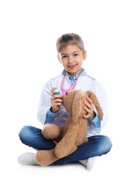 Photo of Cute child playing doctor with stuffed toy on white background