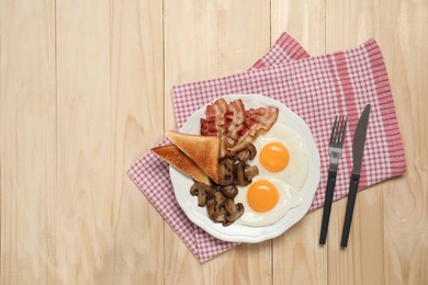 Photo of Plate of fried eggs, mushrooms, bacon and toasted bread on wooden table, flat lay with space for text. Traditional English breakfast