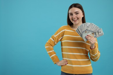 Photo of Happy woman with dollar banknotes on light blue background, space for text