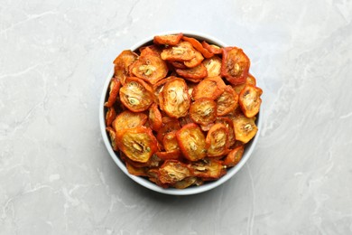 Photo of Bowl with cut dried kumquat fruits on white marble table, top view