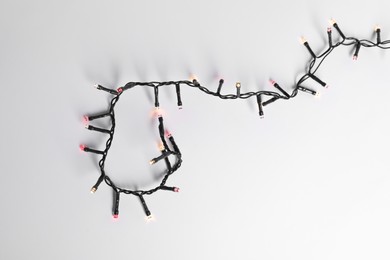 Photo of Beautiful Christmas lights on white background, top view