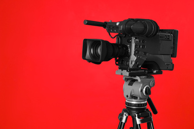 Photo of Modern professional video camera on red background