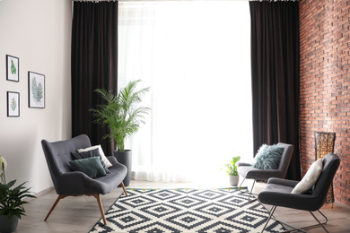 Photo of Comfortable sofa and chairs near window with elegant curtains in room