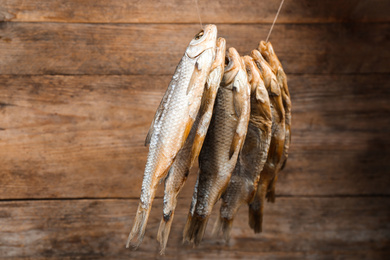 Photo of Dried fish hanging on rope against wooden background