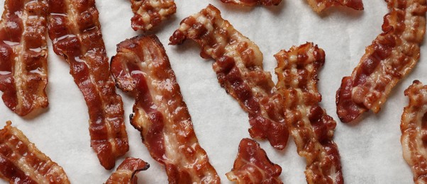 Photo of Slices of tasty fried bacon on white table, top view