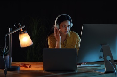 Photo of Programmer with headphones working in office at night