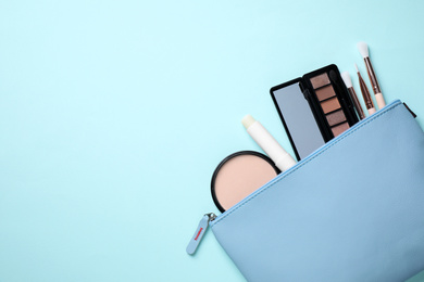 Photo of Bag with hygienic lipstick and cosmetic products on turquoise background, flat lay. Space for text