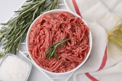 Photo of Flat lay composition with fresh raw ground meat and rosemary in bowl on light table