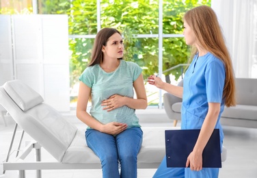 Photo of Young pregnant woman with depression and her doctor in clinic