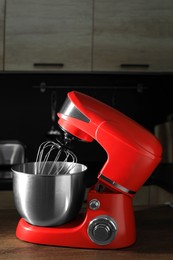 Photo of Modern red stand mixer on wooden table in kitchen