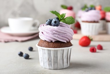 Photo of Delicious cupcake with cream and blueberries on light grey table