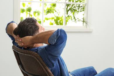 Photo of Man relaxing in armchair near window at home