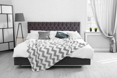 Photo of Bed with pillows and plaid in modern room interior