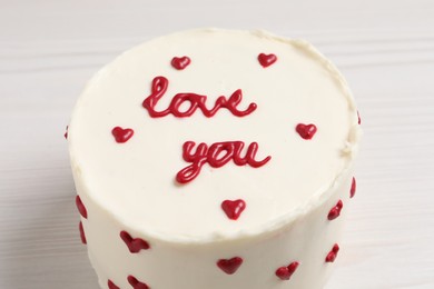 Photo of Bento cake with text Love You on white wooden table, closeup. St. Valentine's day surprise