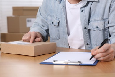 Photo of Seller with parcel and clipboard working at workplace, closeup. Online store
