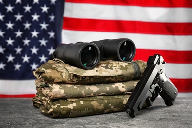 Photo of Military clothes, gun and binocular on table against American flag background