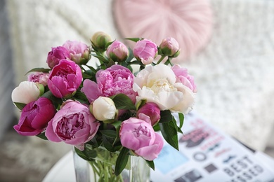 Photo of Vase with bouquet of beautiful peonies on table in room, space for text