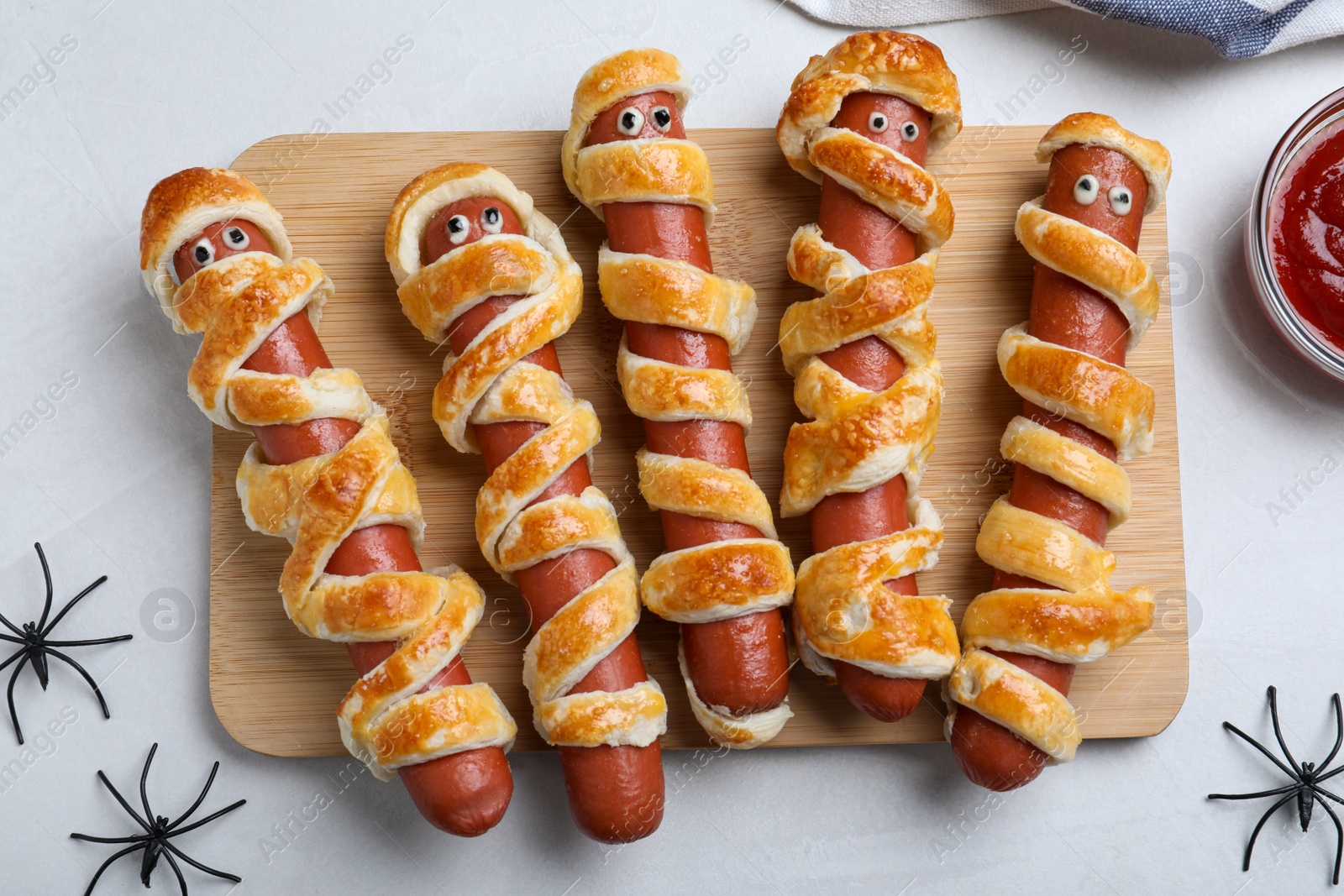 Photo of Cute sausage mummies served on white table, flat lay. Halloween party food