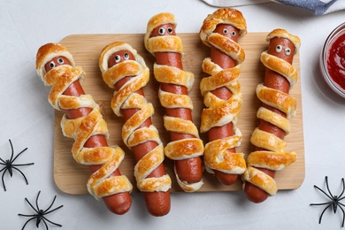 Cute sausage mummies served on white table, flat lay. Halloween party food