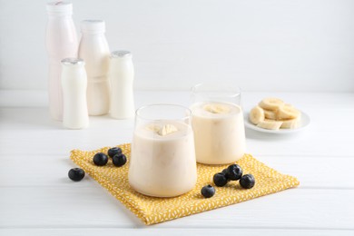 Photo of Tasty yogurt, banana and blueberries on white wooden table