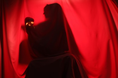 Photo of Silhouette of creepy ghost with skull behind red cloth