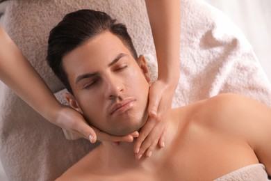 Photo of Man receiving facial massage in beauty salon, top view