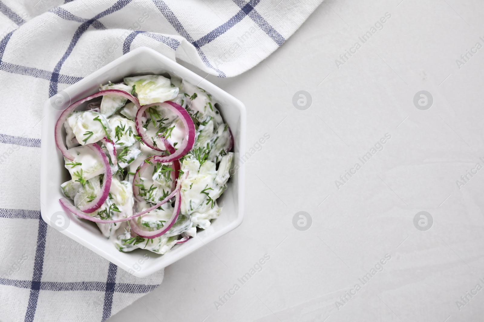Delicious fresh cucumber onion salad with dressing in bowl on table, top view. Space for text Photo of Delicious fresh cucumber onion salad with dressing in bowl on table, top view. Space for text