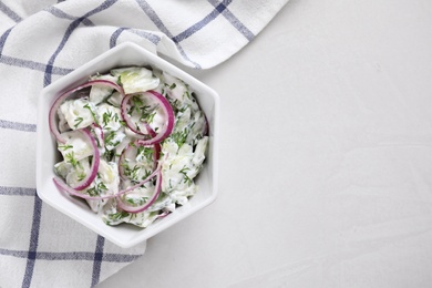 Photo of Delicious fresh cucumber onion salad with dressing in bowl on table, top view. Space for text