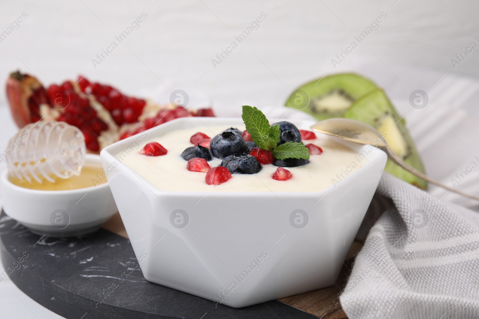Bowl of delicious semolina pudding with blueberries, pomegranate and mint served on table, closeup Photo of Bowl of delicious semolina pudding with blueberries, pomegranate and mint served on table, closeup