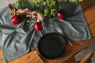 Photo of Set of clean dishware, ripe red apples and flowers on dining table, above view