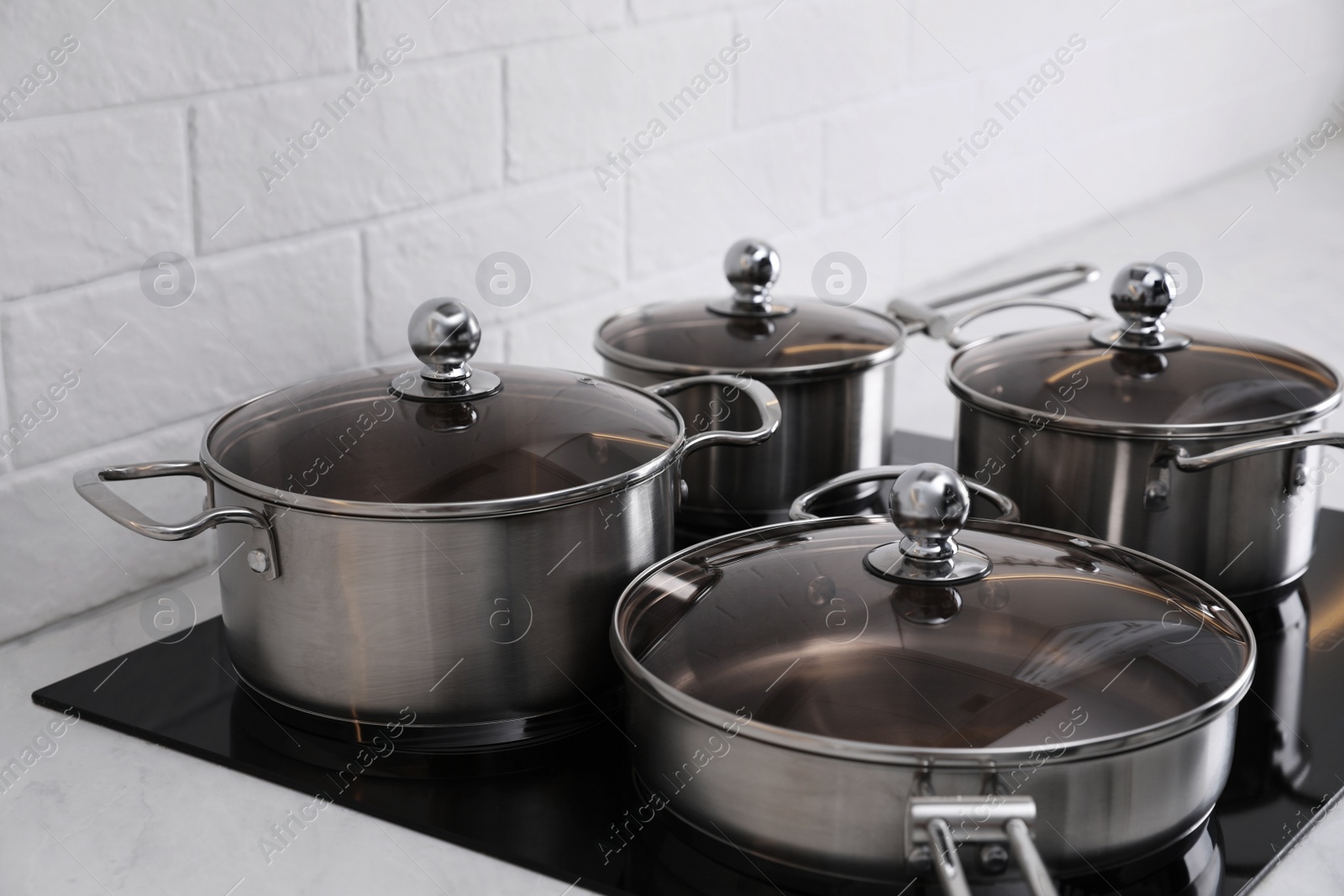 Photo of Set of new clean cookware on cooktop in kitchen, closeup