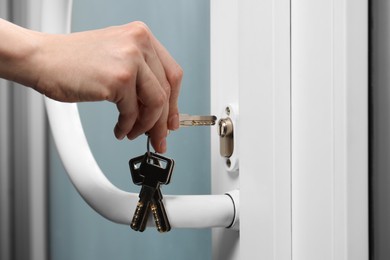 Photo of Woman unlocking door with key, closeup view