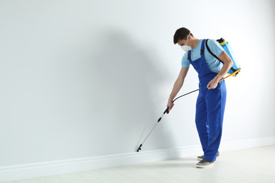 Photo of Pest control worker spraying pesticide in room. Space for text