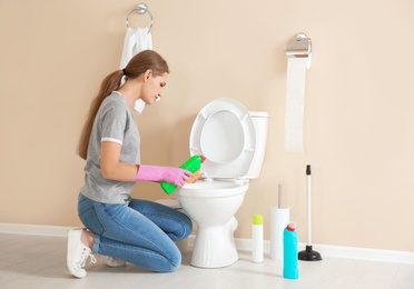 Photo of Woman cleaning toilet bowl in bathroom