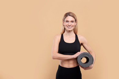 Photo of Athletic woman with fitness mat on beige background, space for text