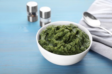 Photo of Bowl with green tasty puree on light blue wooden table