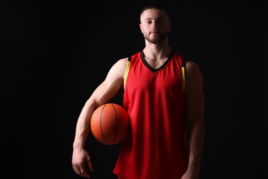 Photo of Athletic young man with basketball ball on black background