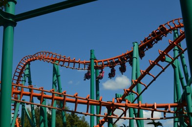 Photo of Amusement park. Beautiful large colorful rollercoaster against blue sky