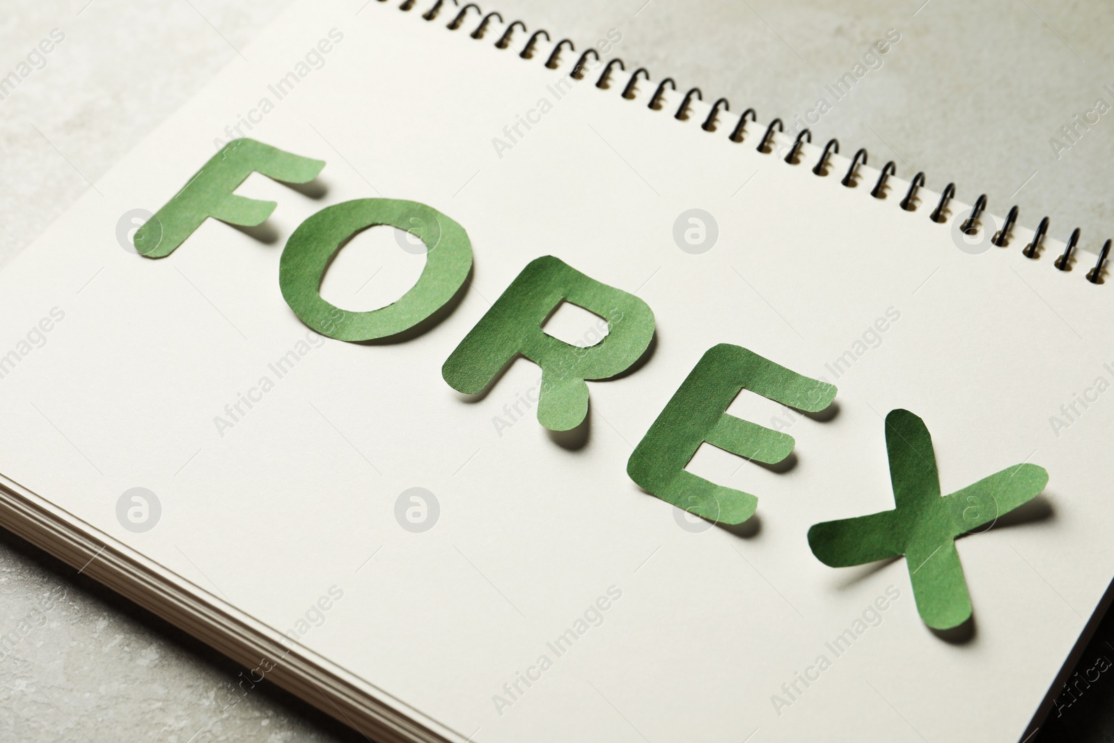 Photo of Notebook with word Forex made of green letters on grey table