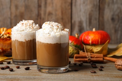 Photo of Glasses with tasty pumpkin spice latte on wooden table