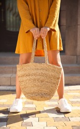 Photo of Woman in stylish yellow dress and sneakers with handbag on city street, closeup