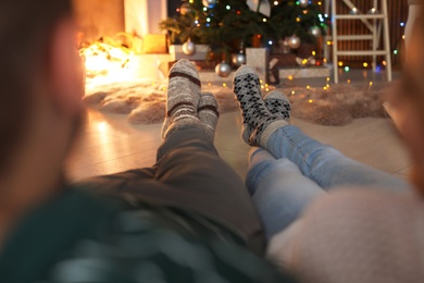 Photo of Young couple in warm socks celebrating Christmas at home, focus on legs