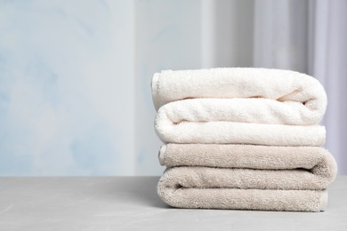Photo of Stack of soft bath towels on table against blurred background. Space for text
