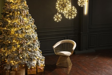 Photo of Beautiful decorated Christmas tree, chair and festive decor indoors, space for text. Interior design