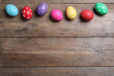 Photo of Colorful eggs on wooden background, flat lay with space for text. Happy Easter
