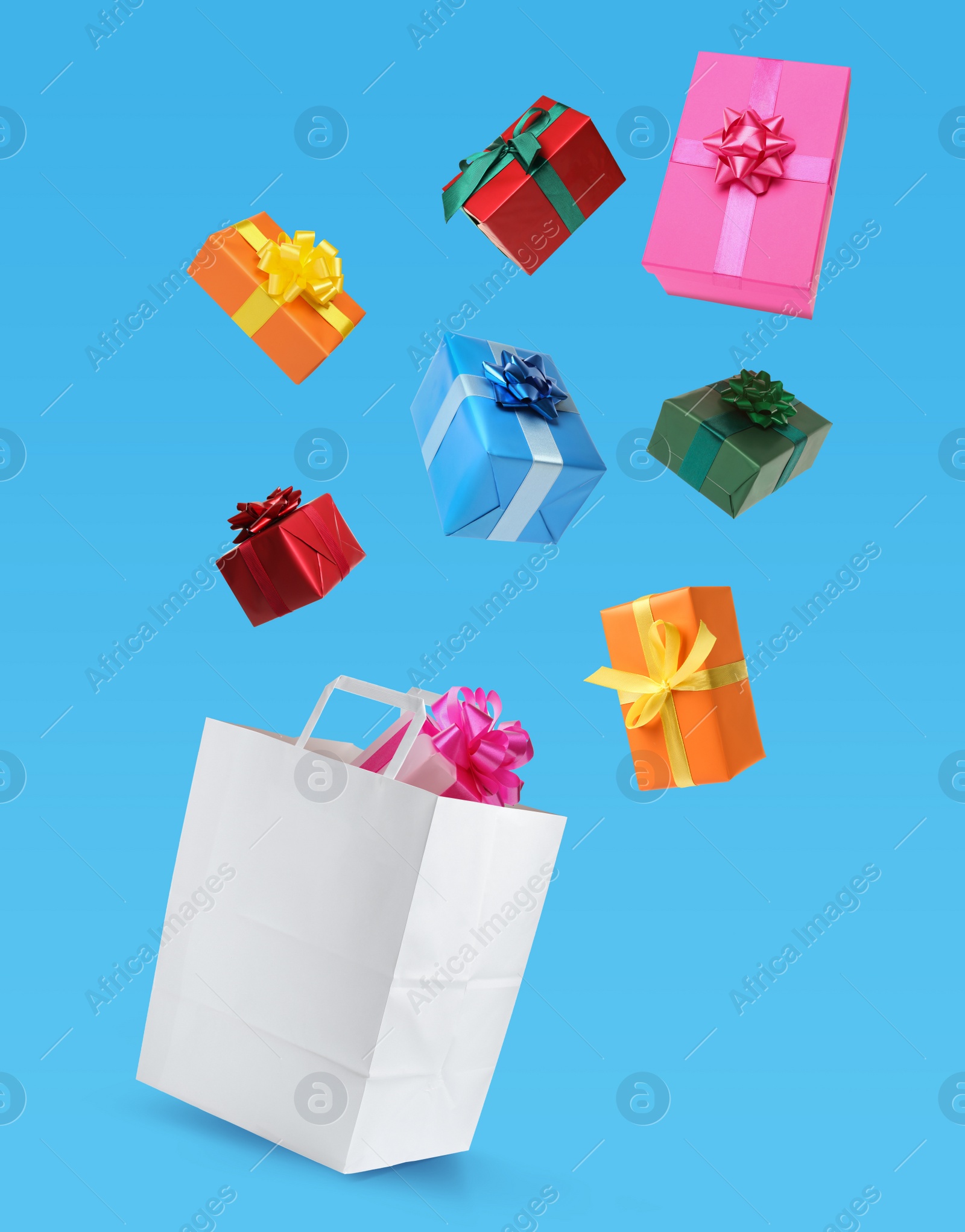 Image of Many different gift boxes falling into paper shopping bag on light blue background