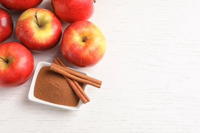 Photo of Fresh apples with cinnamon sticks and powder on wooden table