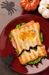 Photo of Cute monster sandwich with fried eggs on grey textured table, flat lay. Halloween snack