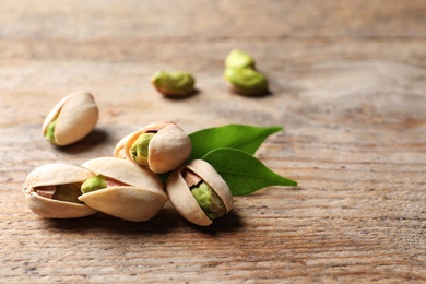 Photo of Organic pistachio nuts on wooden table. Space for text